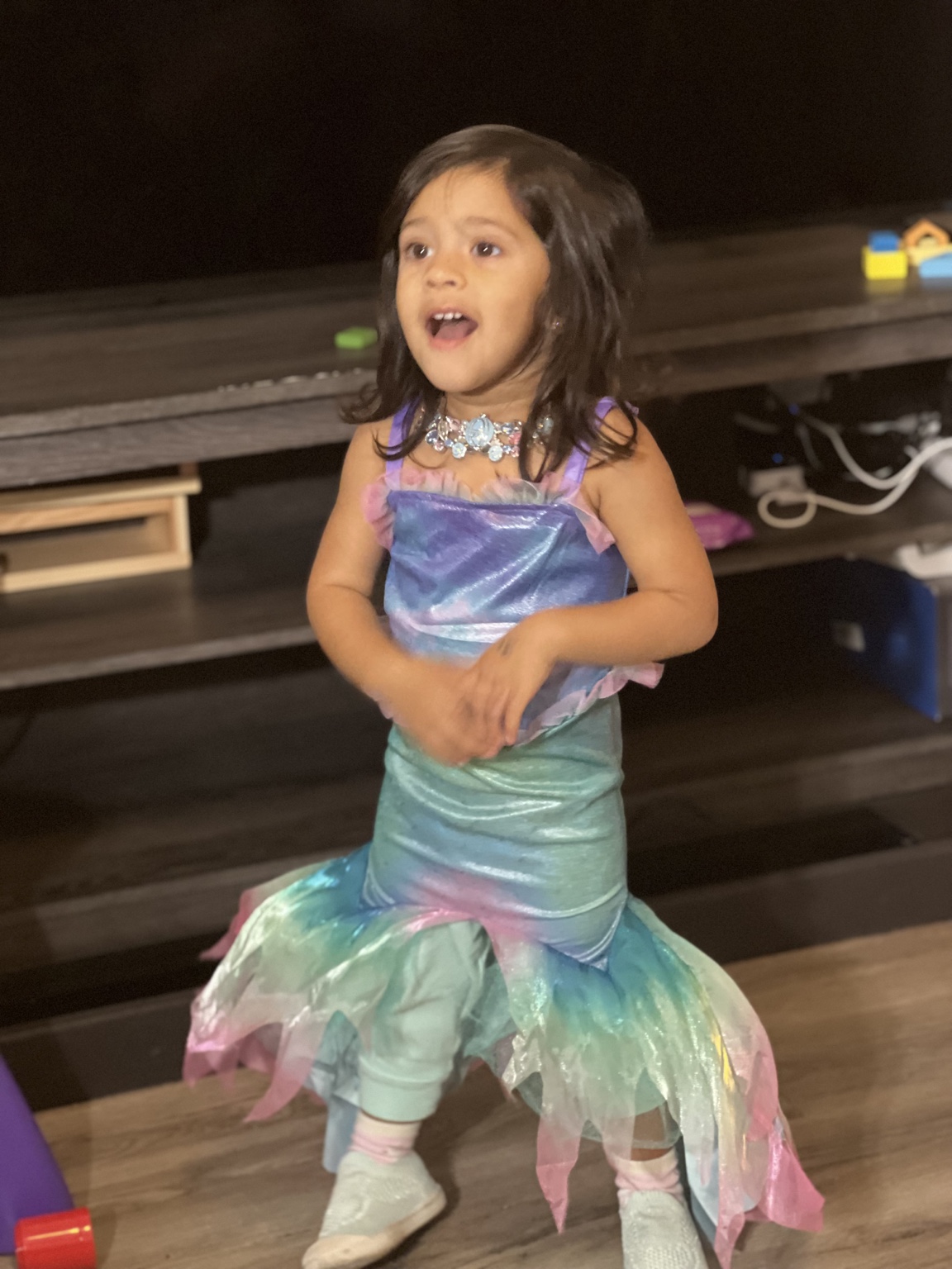Aria dressed as a shimmering mermaid, singing at the top of her lungs