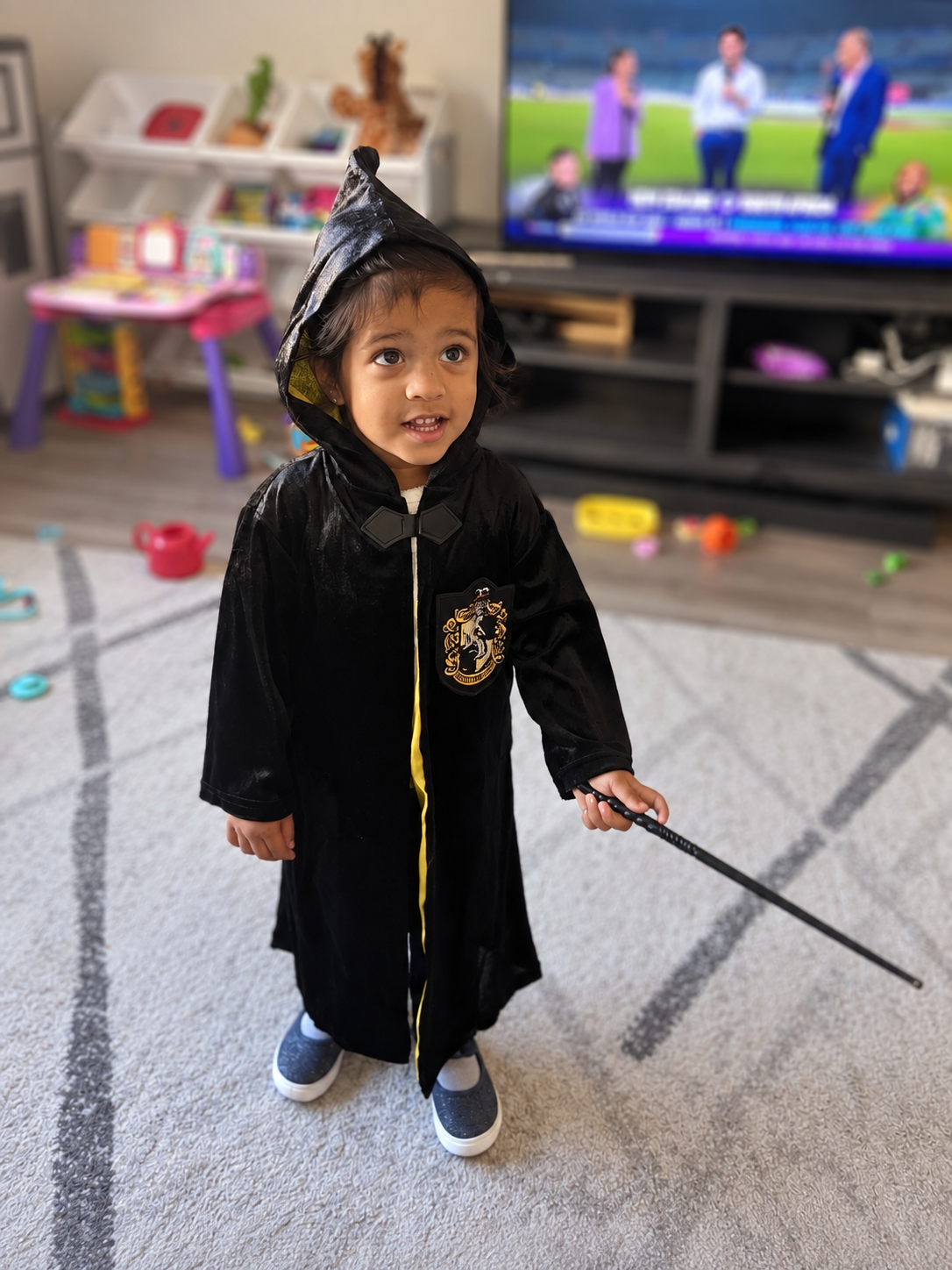 Aria in a black witch robe and hat, wand in hand