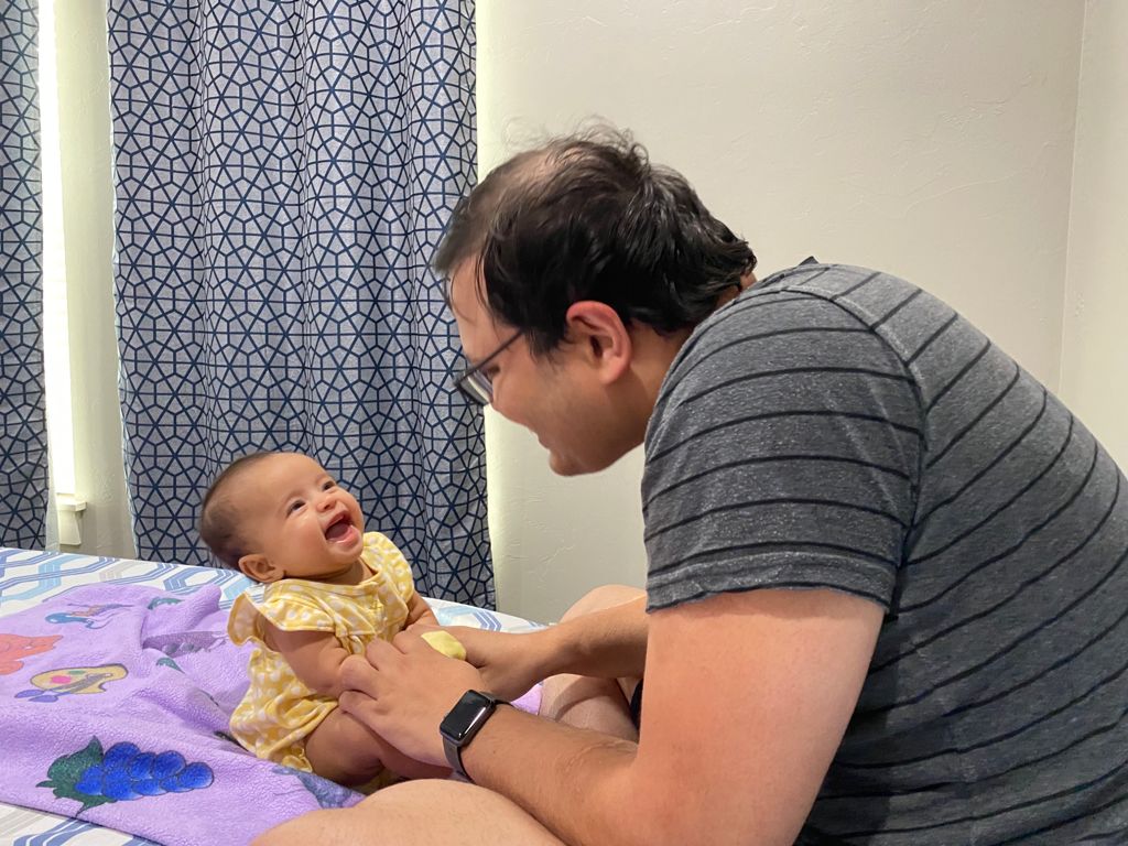 Daddy tickling baby Aria while she laughs on the bed