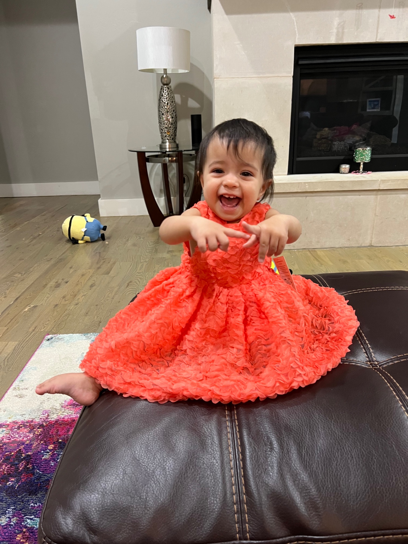 Aria laughing in her bright orange dress, pointing with both hands