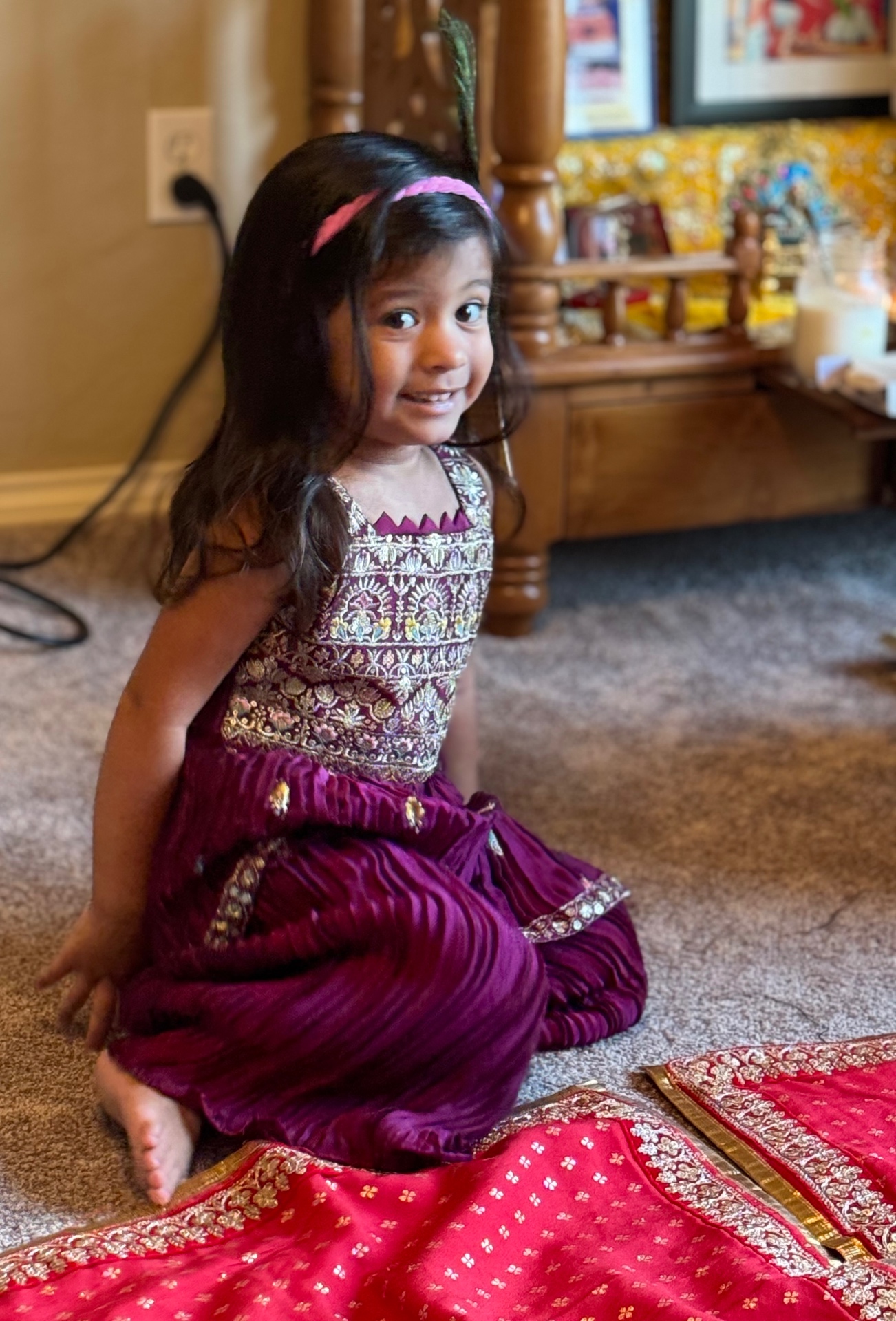 Aria in a beautiful purple and gold Indian lehenga, smiling from the floor