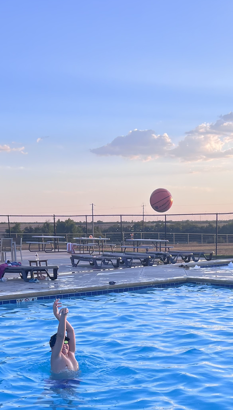 A child shooting a basketball into the Pepper's Ranch pool at sunset