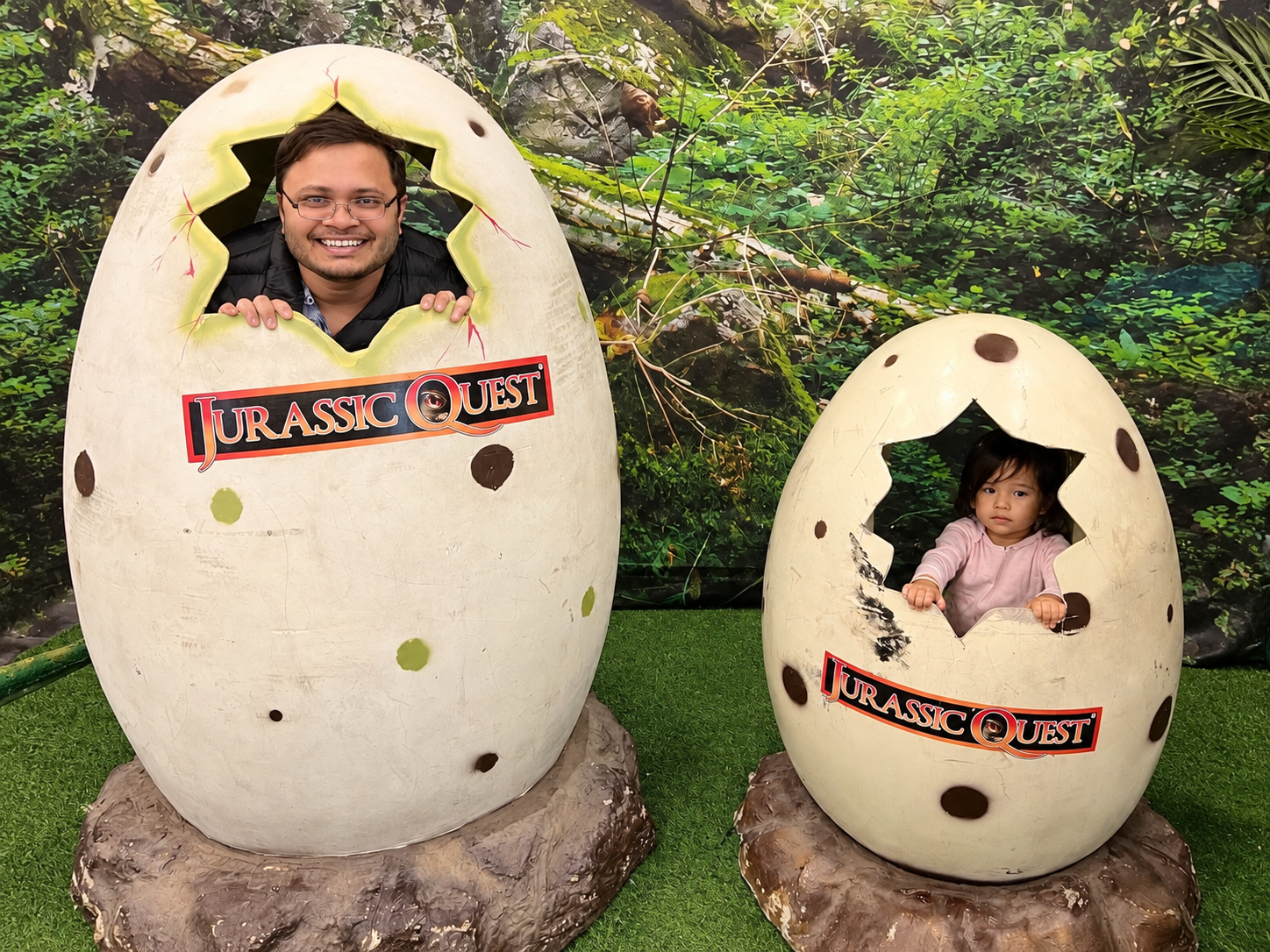 Aria and Daddy peeking out of dinosaur eggs at Jurassic Quest