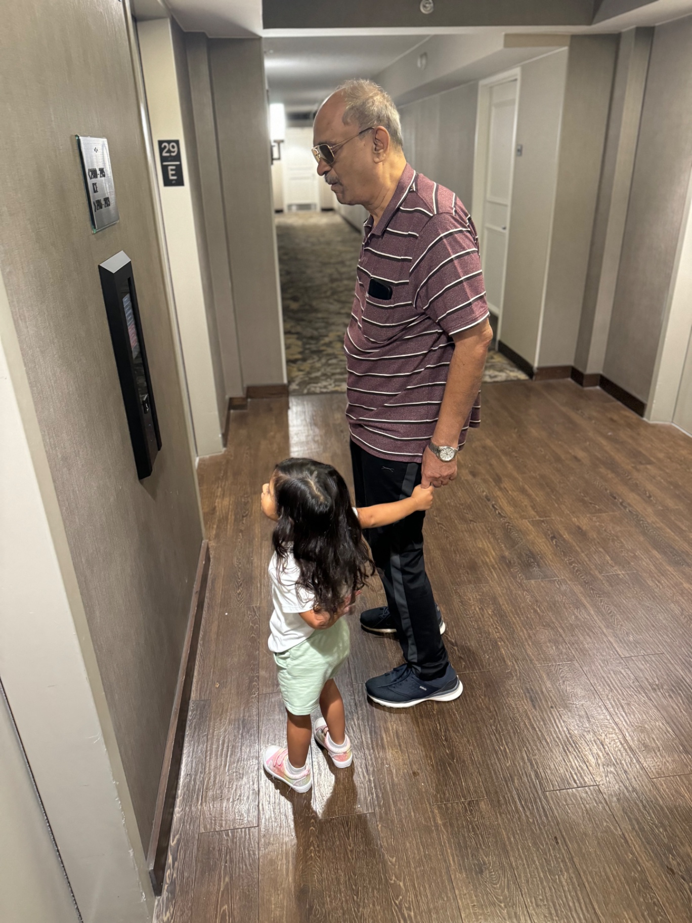 Aria reaching up to hold her grandfather's hand as they walk through a hotel hallway
